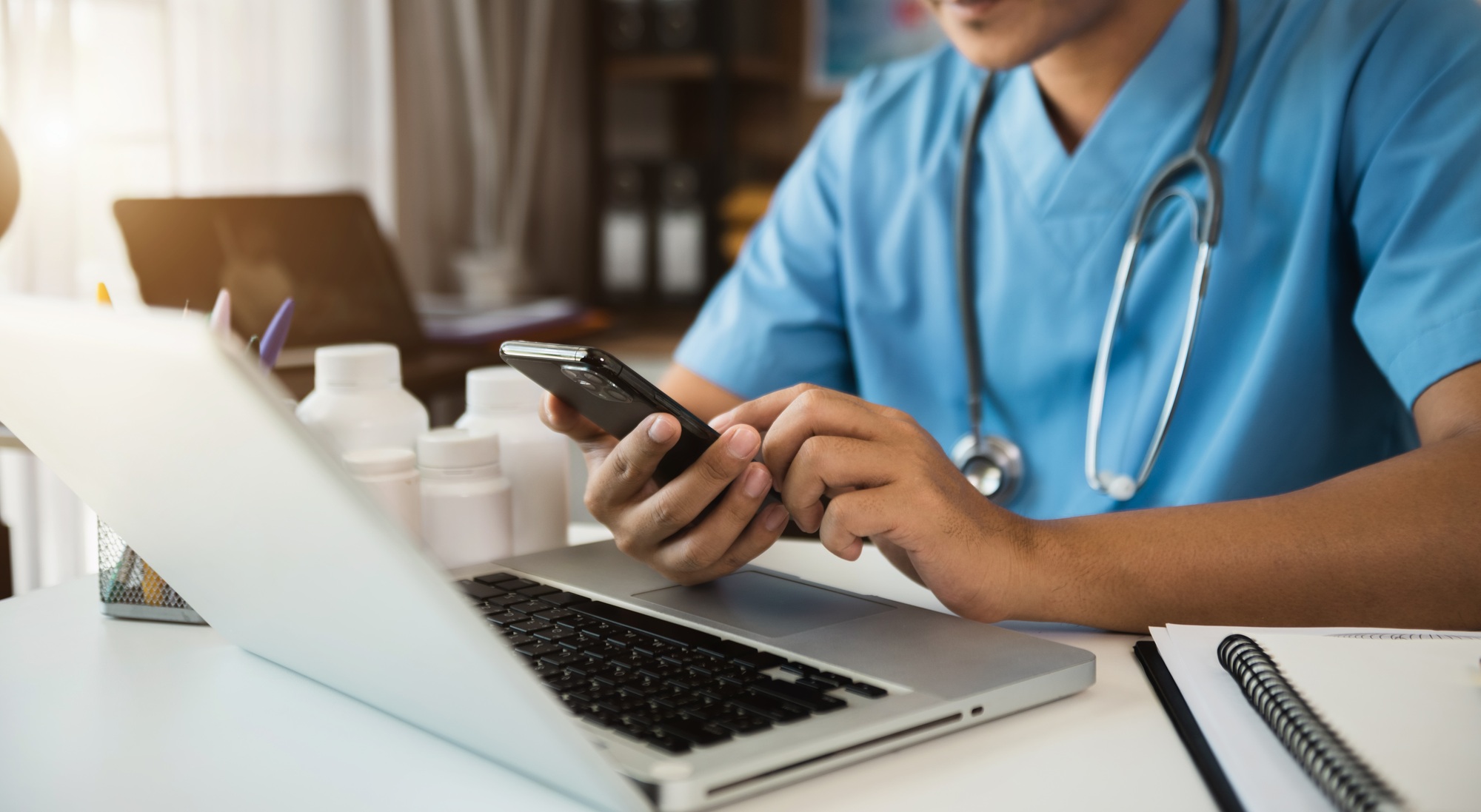 Doctor working with mobile phone and digital tablet laptop in modern office at hospital.